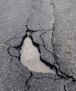 small pothole in road filled with water