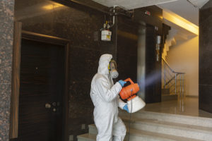 One man in protective suit disinfecting the Apartment entry