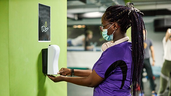 customer cleans with hand sanitizer gym provides in california