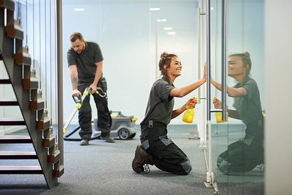 Uniformed janitorial workers cleaning and vacuuming.