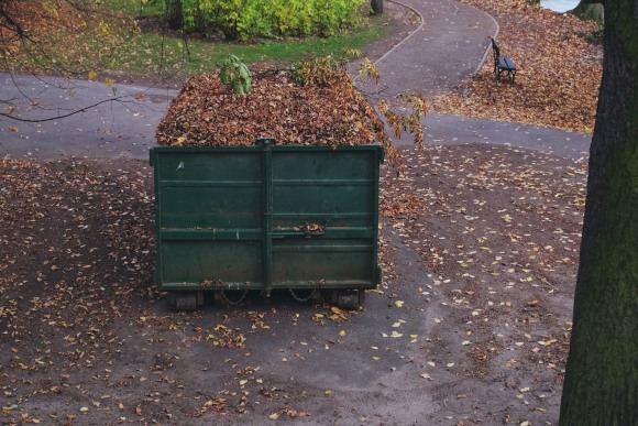 Dumpster Bin Full of Dry Fall Leaves Professional Cleaner Wiping Down Glass