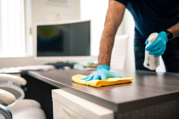 Sanitation Professional Wiping Down Office Desk